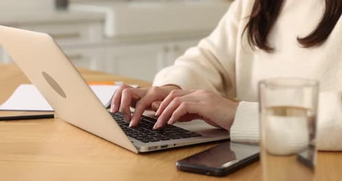 Woman working with laptop at wooden desk in home office, closeup