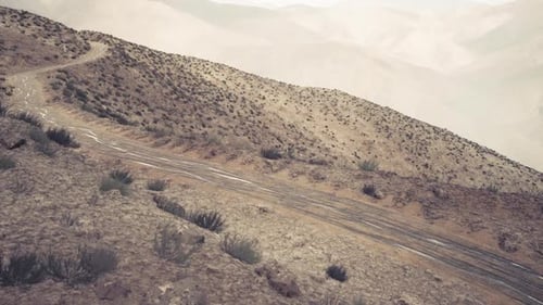 Route de terre sinueuse serpentant à travers les montagnes du Pamir au Tadjikistan au crépuscule