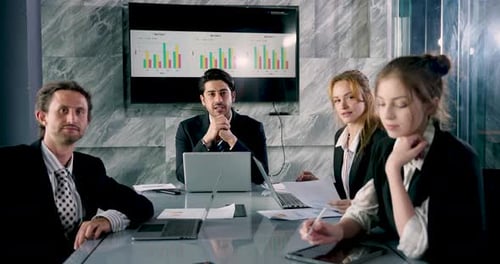 Business Professionals Meeting in Modern Boardroom Discussing Charts