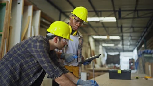 Side view of African American carpenter or woodworker or charpentier man use tablet to consult and d
