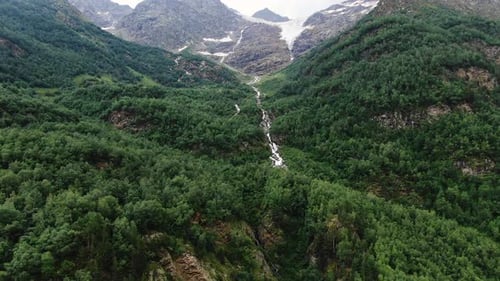 Aerial Shot Capture the Rugged Beauty of a Mountainous Region with a Dense Forest and a Cascading