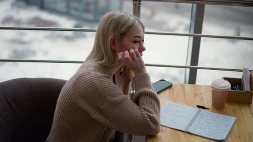 Young Woman Writing in a Notebook in an Urban Setting
