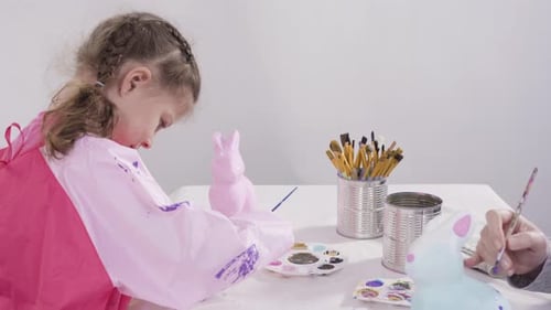 Little Girl Painting Paper Mache Figurines with Acrylic Paint for Her Homeschooling Art Project