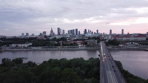 Cinematic drone footage of Warsaw skyline with vistula river and bridge filled with traffic flowing