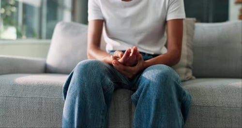 Hands, mental health and person on sofa with anxiety, stress or emotions in living room at home