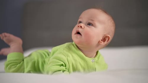 Baby Lying on Stomach Wearing Green Pajamas