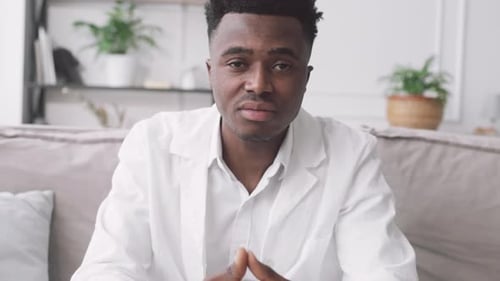 Man in White Coat Talking to Camera Indoors