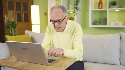 Senior Man Using Laptop, Puts on Glasses