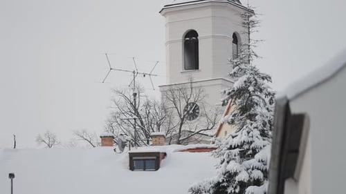 A church belfry covered with snow and surrounded by residential buildings in a quiet neighborhood in