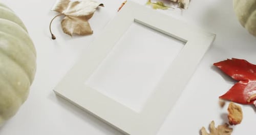 Empty frame with copy space, pumpkin and autumn leaves against white background