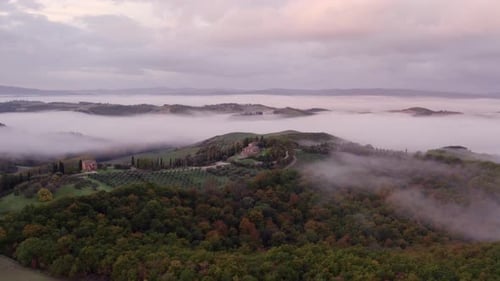 Aerial view of foggy sunrise over countryside with villa, Italy.