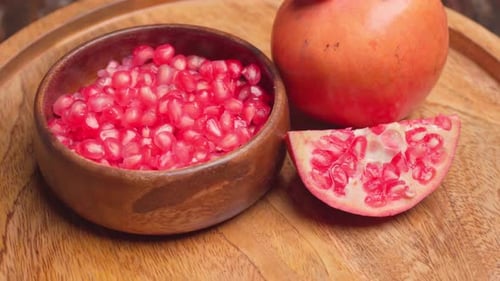 Pomegranate Seeds in Bowl with Whole Pomegranate