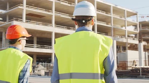 Professional Builders Standing in Front of Construction Site Office Building and Crane Background