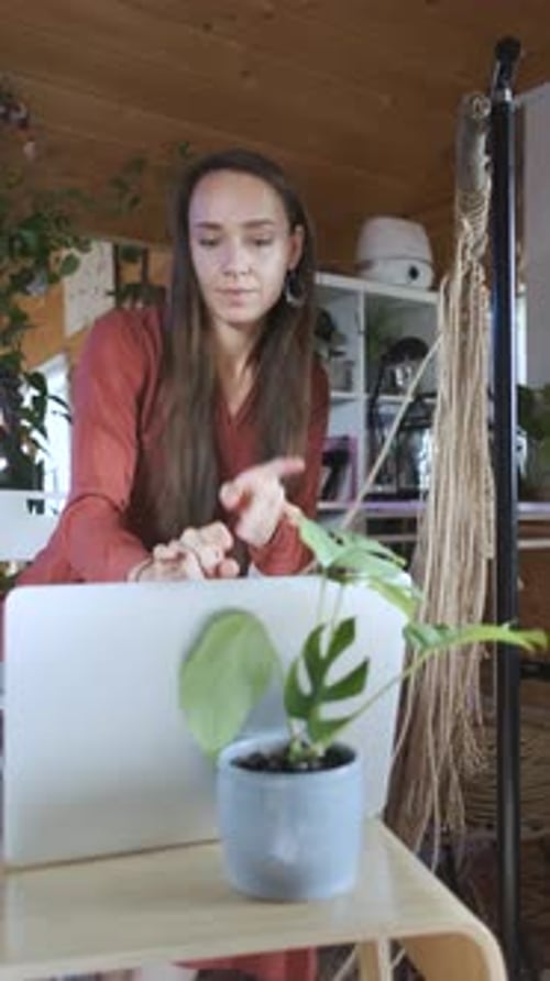 woman learning to weave macrame by video on laptop, vertical video