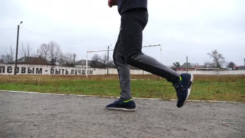 Jambes d'un jeune sportif courant sur une piste d'athlétisme Pieds masculins d'un coureur sportif faisant du jogging