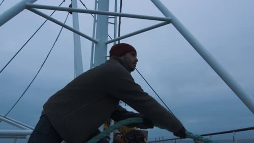 Man Pulling Blue Rope on Boat on Overcast Day