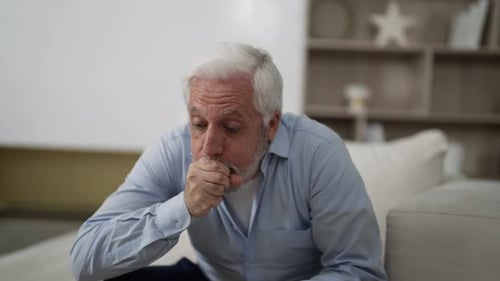 Un homme âgé se sent mal et a une toux terrible, un homme âgé aux cheveux gris souffrant d'asthme