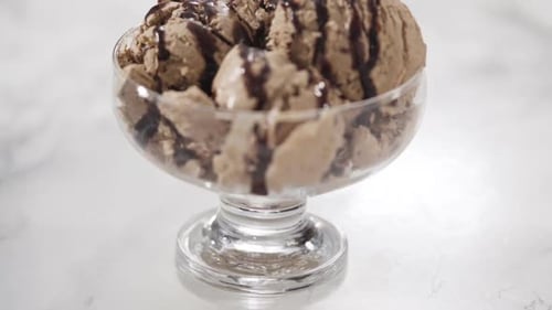 Helado de chocolate casero adornado con chocolate en un tazón de helado de vidrio
