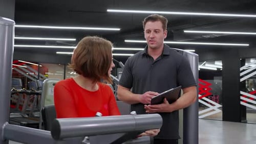 Woman Working Out at Gym with Trainer
