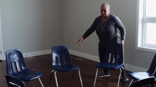 Female Volunteer Arranging Chairs in Circle in Community Center 6064 Years