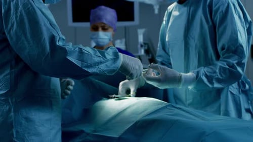 In the Hospital Operating Room Diverse Team of Professional Surgeons and Nurses Suture Wound after