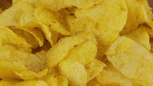 Potato chips rotating close up on a wooden board.