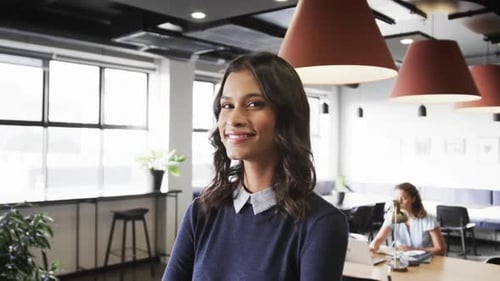Portrait of happy biracial casual businesswoman in office, slow motion