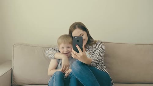 Happy Mother and Child Video Chatting on Couch