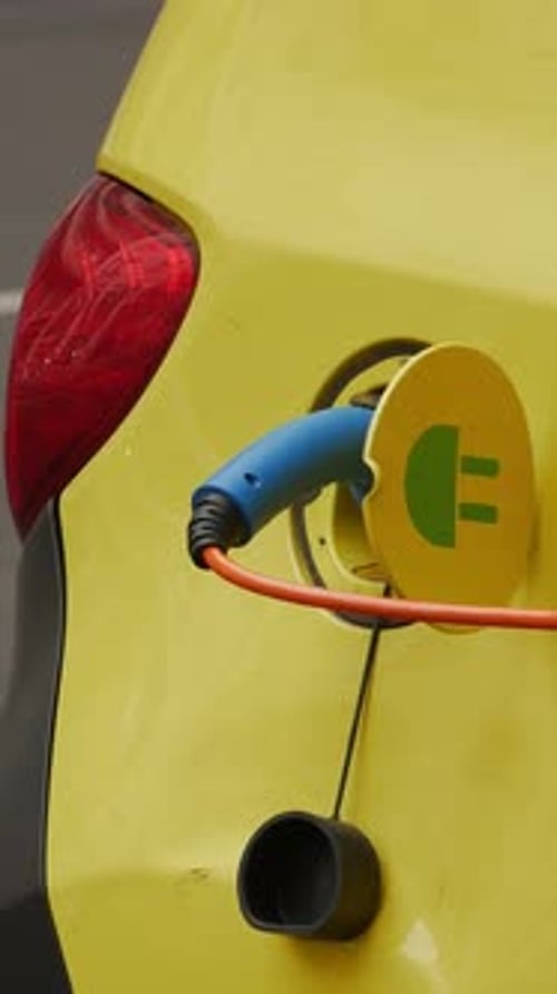 Yellow EV Car Being Charged Outdoors Reflecting Modern Mobility Solutions Close Up Vertical Video