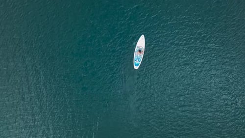 Aerial View Paddleboarding Across Emerald Waters Framed By Dramatic Peaks and Unique Dry Trees