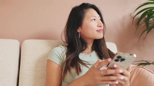 Close-up of a young woman sitting on a sofa with a mobile phone in her hands