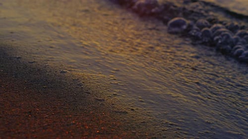 Golden sunset reflections on calm sea waves at dusk on a beautiful beach