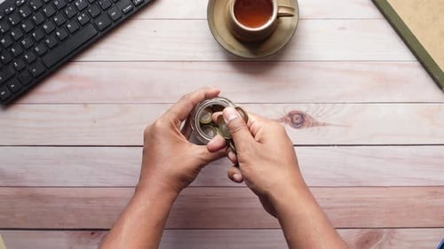 Top View of Young Man Saving Coins in a Jar White Sited