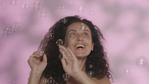 Tender Beautiful Woman with Naked Shoulders in the Studio on a Pink Background with Highlights