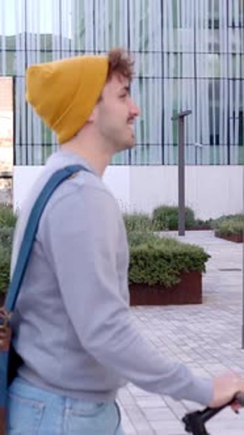 Jovem feliz andando com bicicleta na área externa de um centro de negócios