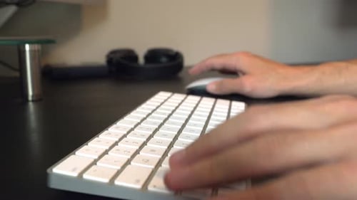 Close up slider shot of man typing on white keyboard and moving mouse