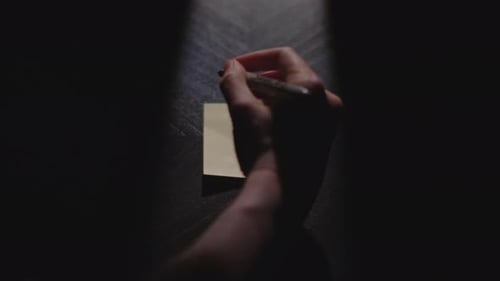 Hand Writes 'Monday' on Sticky Note in Dark