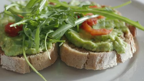 Avocado Toast with Arugula and Tomatoes on Plate