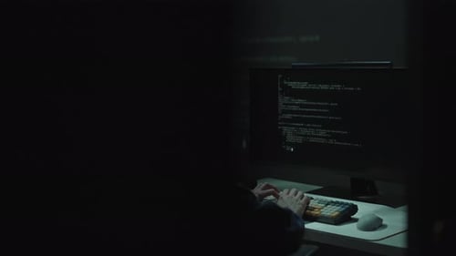 Hacker Typing Code at Computer in Dark Room