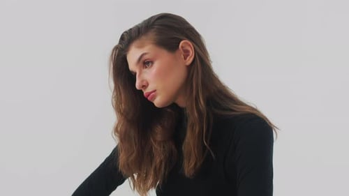 Beautiful Woman with Long Curly Brown Hair Fashion Model Looks to the Camera at Studio Footage Slow