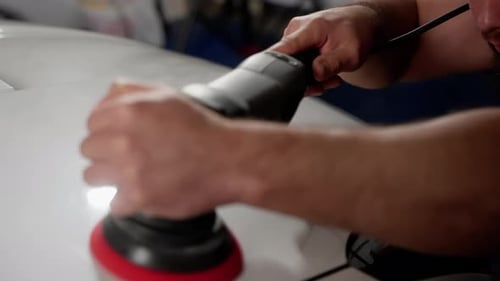 A Man is Polishing a Car with a Polisher