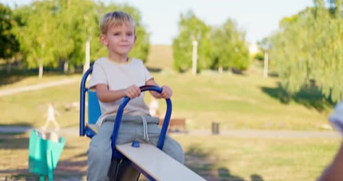 Little Boy Laughing and Having Fun Swinging on Seesaw Board Playing Playground