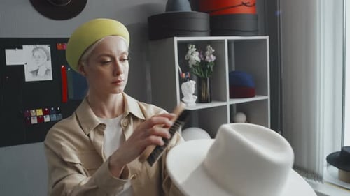 Woman Brushing a Hat in Fashion Studio