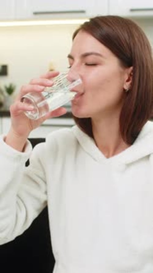 Woman in a White Hoodie Drinking Water