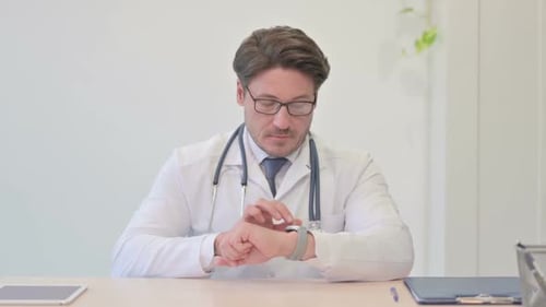 Middle Aged Doctor Using Smart watch in Clinic