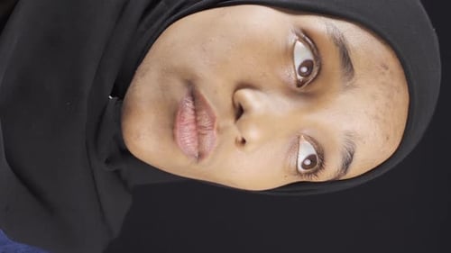 Vertical Video of Portrait of unhappy and thoughtful African muslim young woman in hijab.