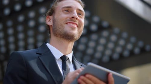 Young businessman uses tablet outdoors on sunny day