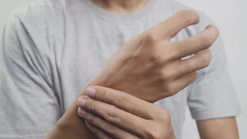 Man Rubs His Sore Wrist in Close Up
