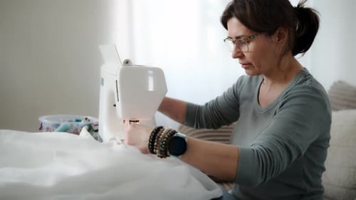 Focused Woman Sewing White Fabric at Home