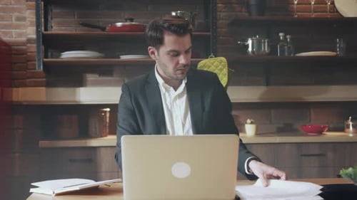 Man in Suit Working on Laptop in Kitchen